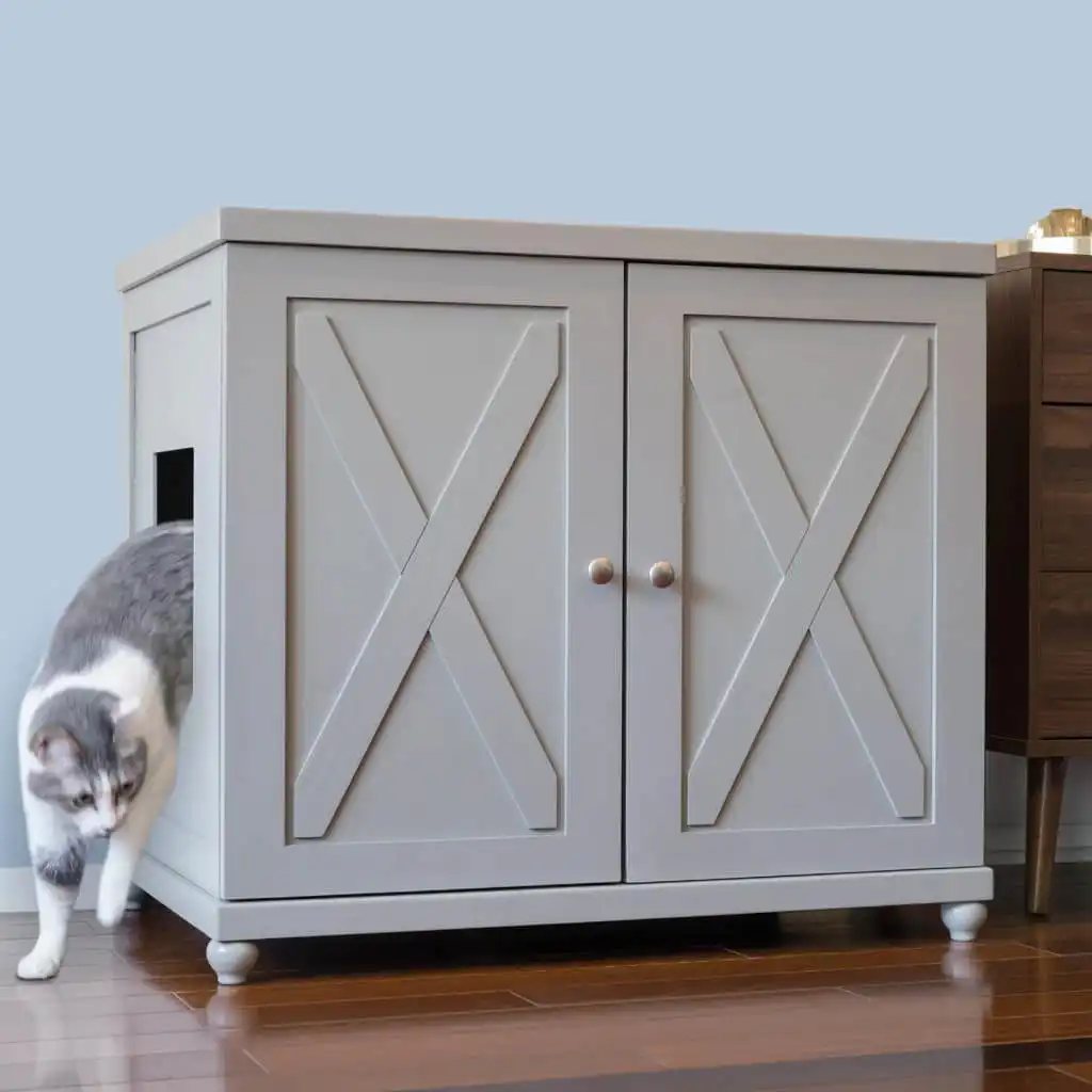 Gray and white cat stepping out of a side-entry litter box cabinet onto a wooden floor.