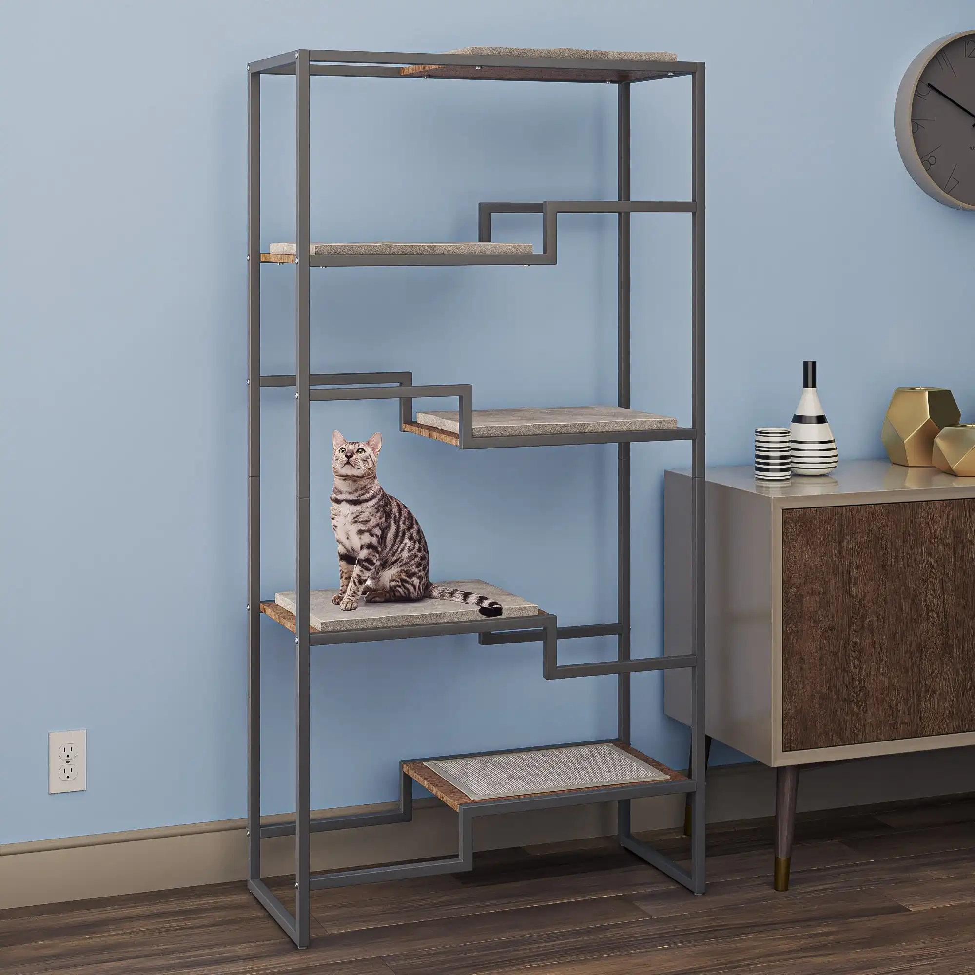 Gray tabby cat sits on the second shelf of a carpeted cat condo in a blue-walled, mid-century styled room.
