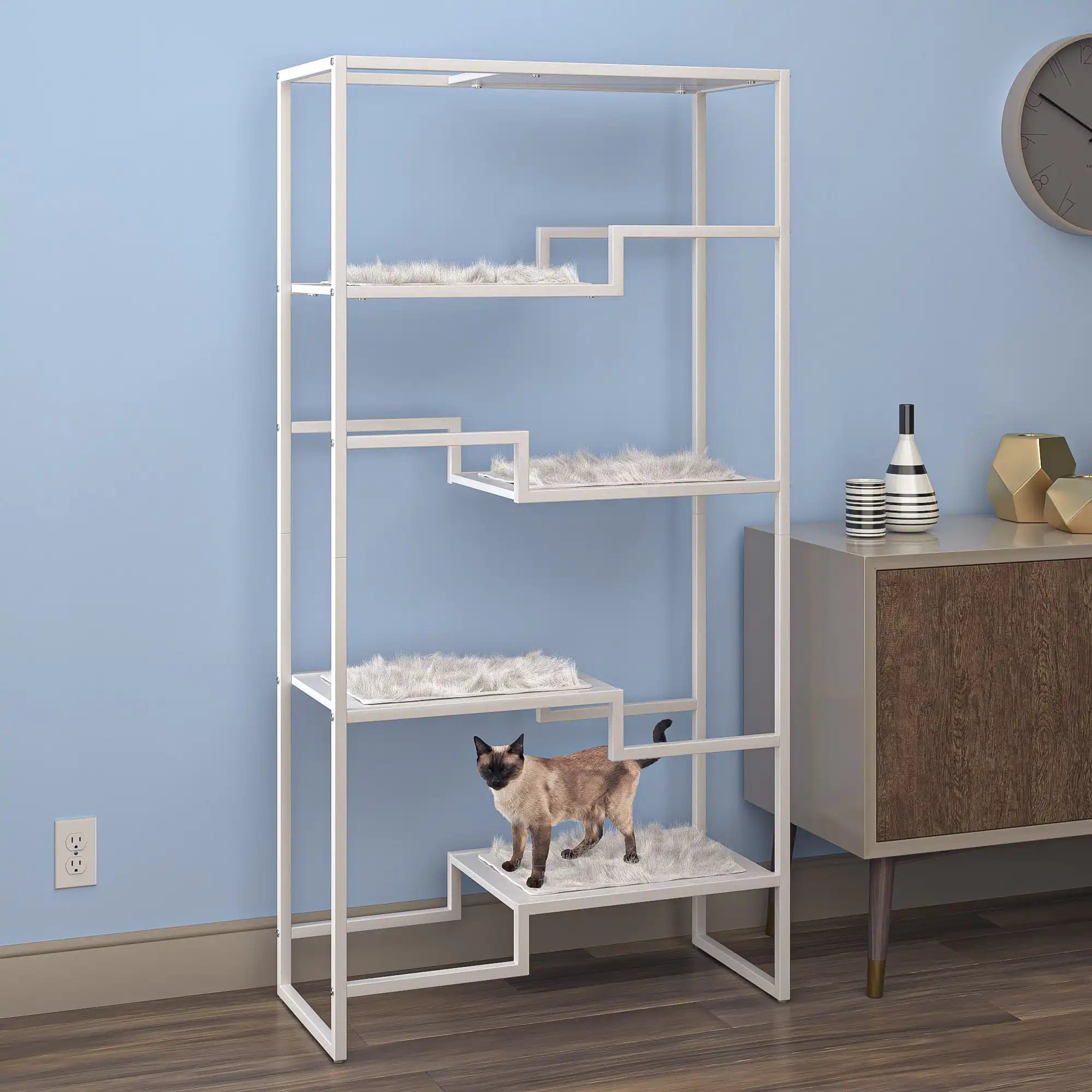 Cat sitting on a multi-tier metal and faux fur condo by a blue wall near a wooden cabinet and decorative objects.