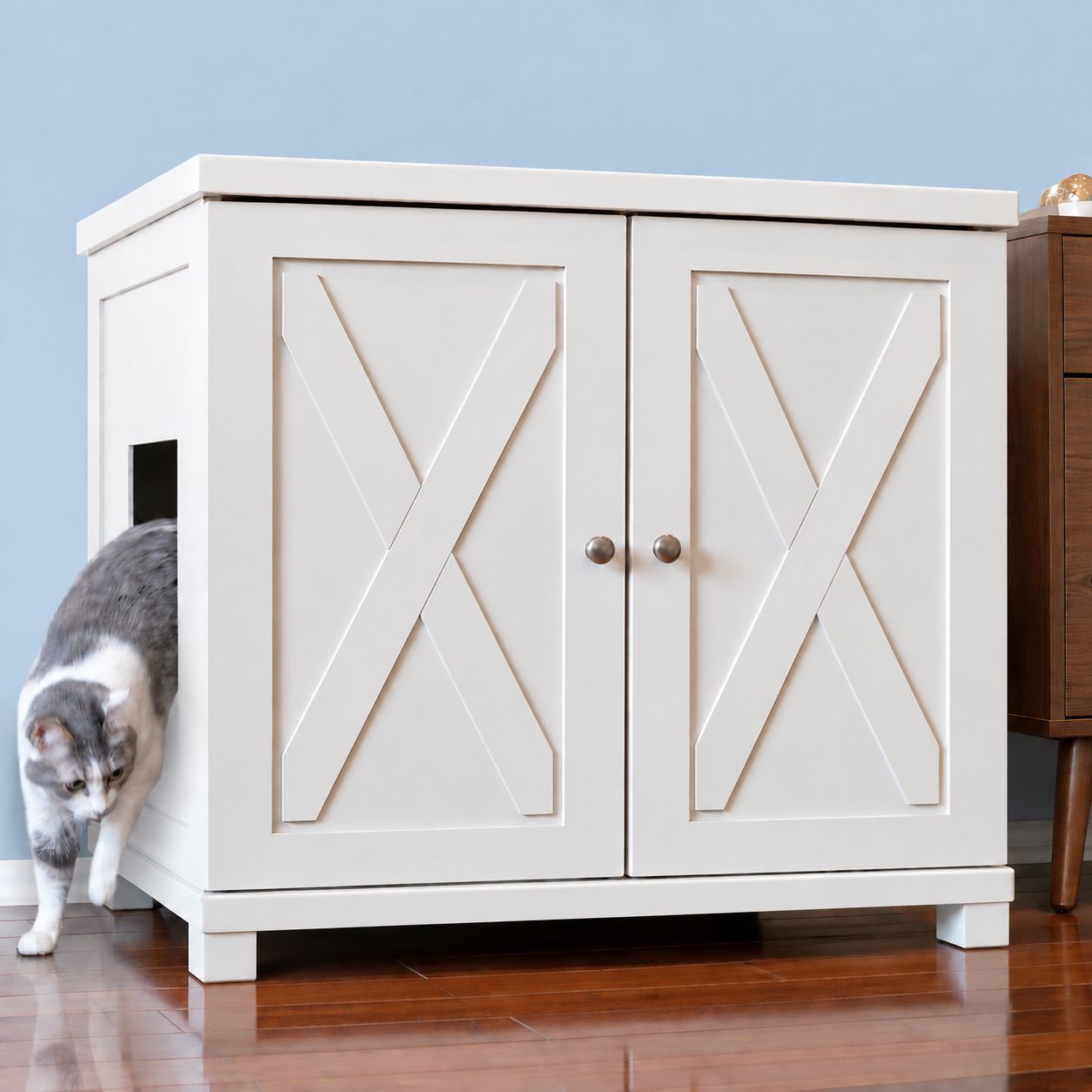 A cat exits a white ERLB-XL-WH-FARM-SQUARE deluxe litter box cabinet with X-patterned doors and a side entry.