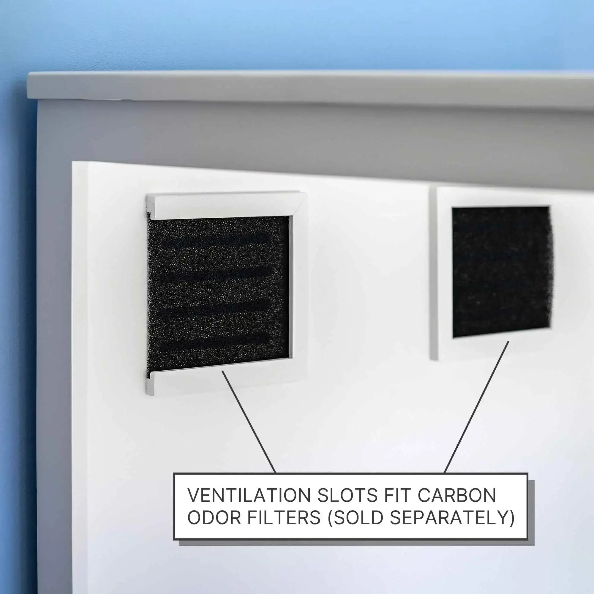 Two rectangular vents with black carbon filters on a white cat litter box panel; label says filters sold separately.