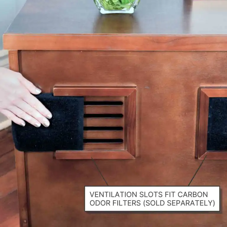 A hand inserts a black carbon odor filter into a wooden litter box vent; on-screen text reads “Filters sold separately.”.