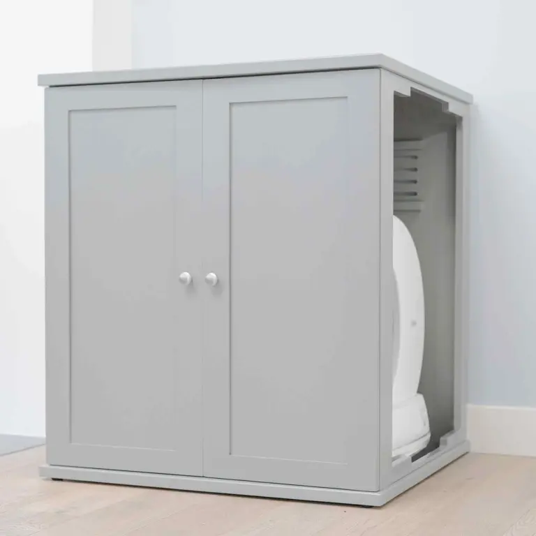 Modern gray cabinet with double doors open right, revealing white self-cleaning litter box inside on wood floor.