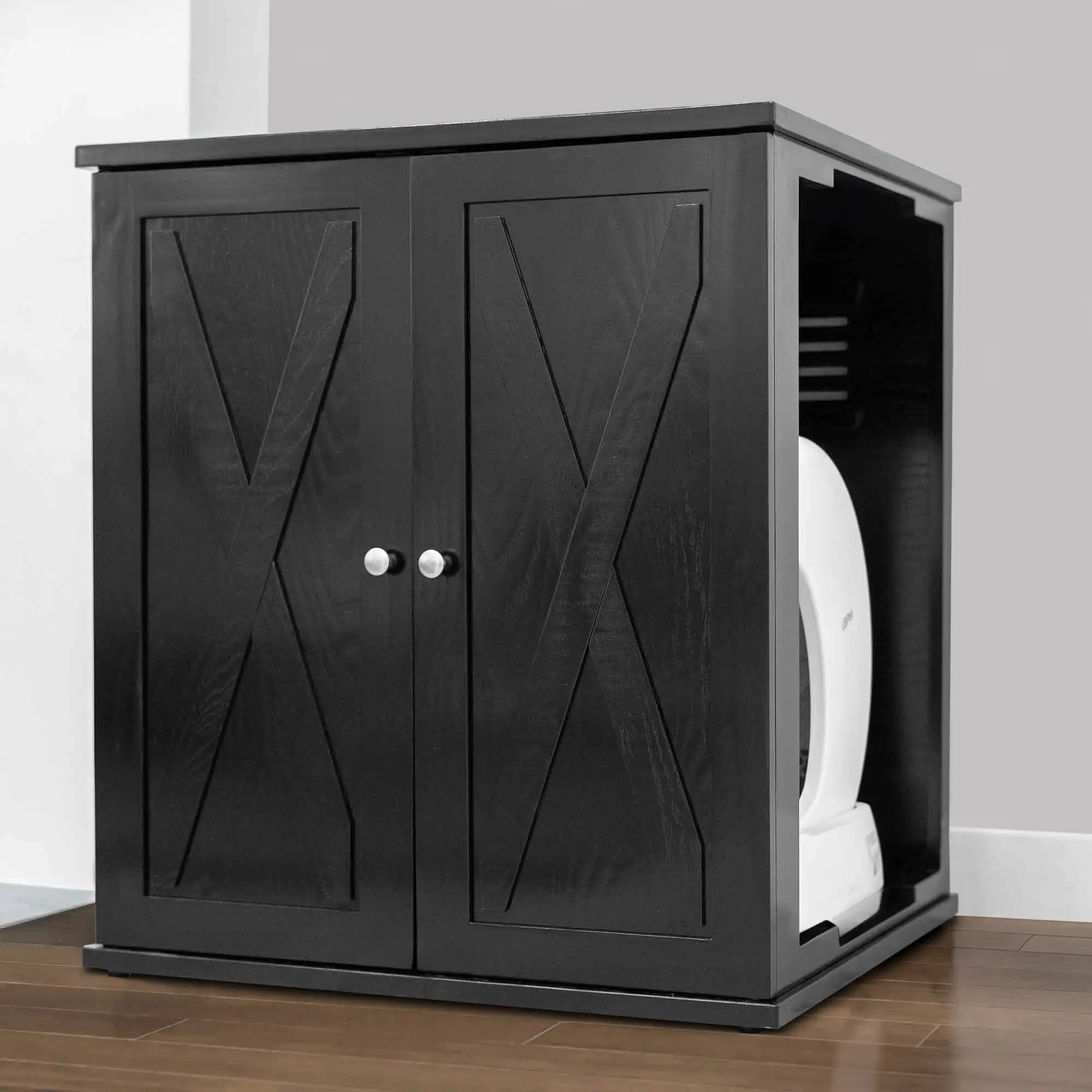 Black wooden cabinet with two open doors reveals a white appliance inside, on a wood floor against a gray wall.